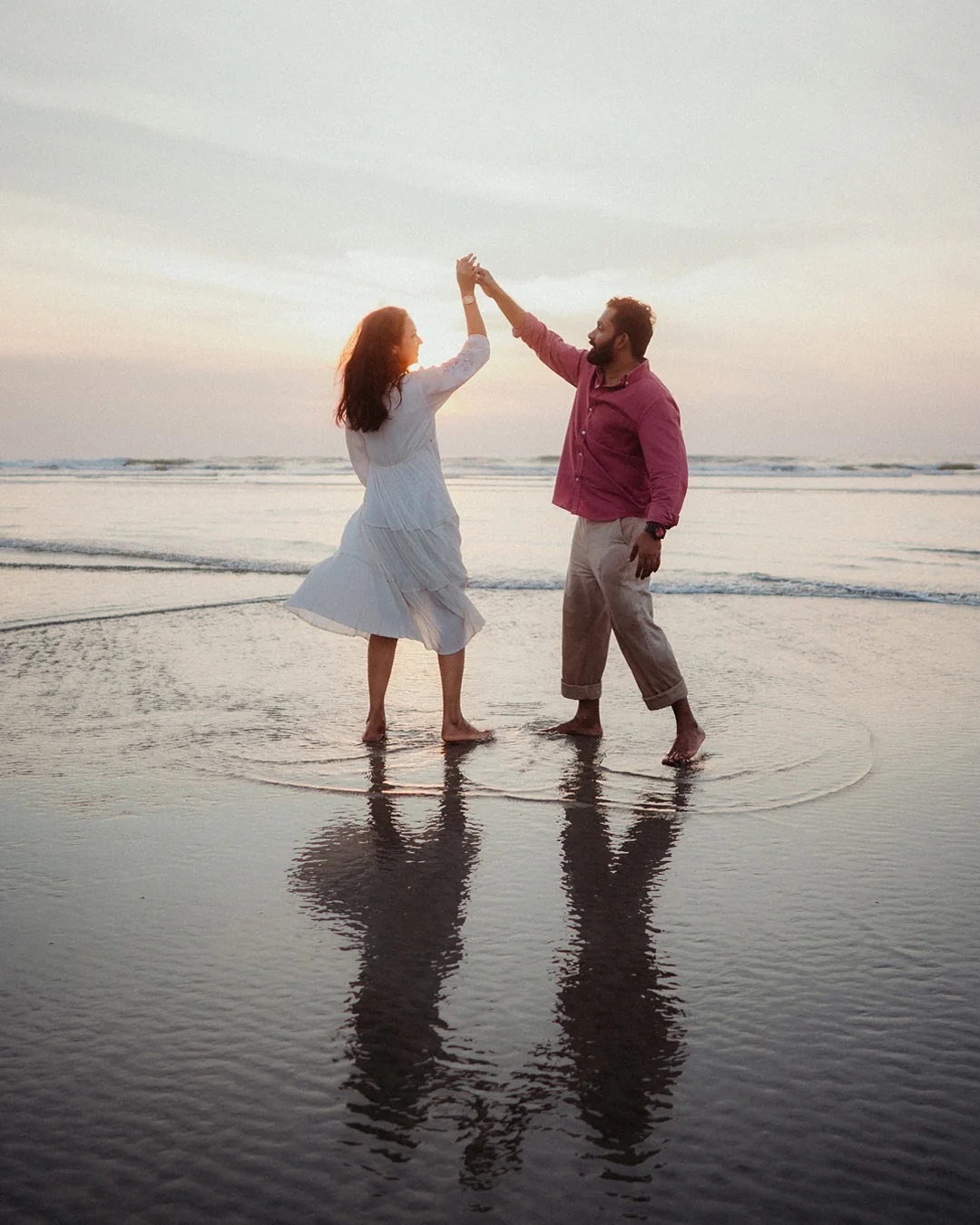 A couple dancing together at the beach at sunset
