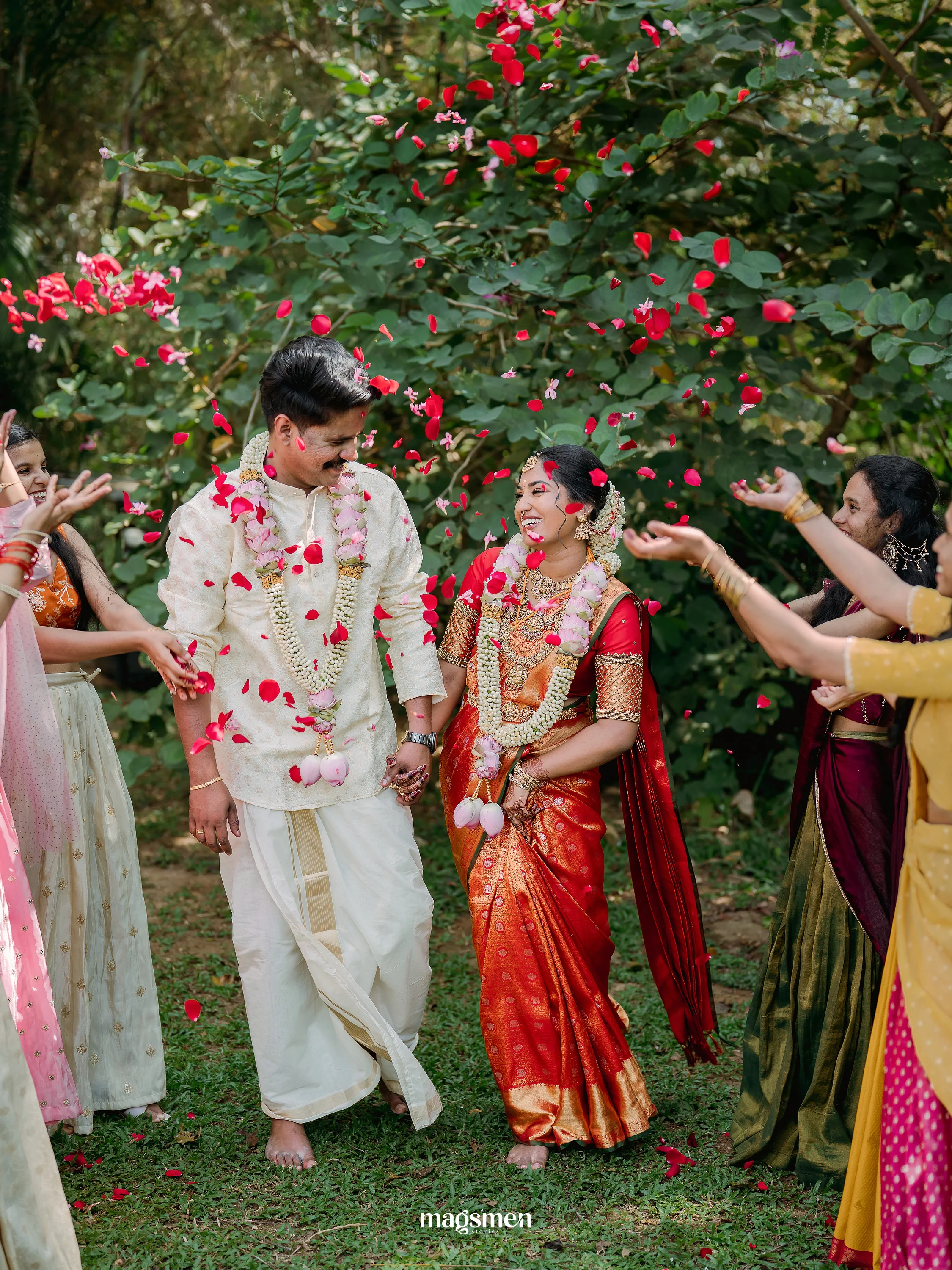 A newlywed couple smiling beneath a shower of rose petals