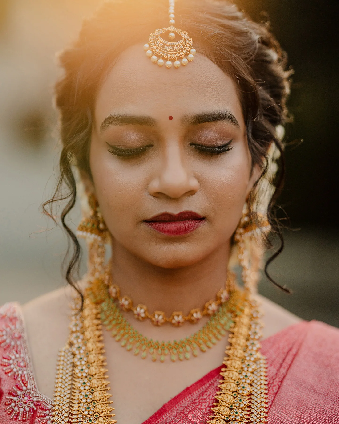 A bride wearing traditional gold jewellery in warm afternoon light